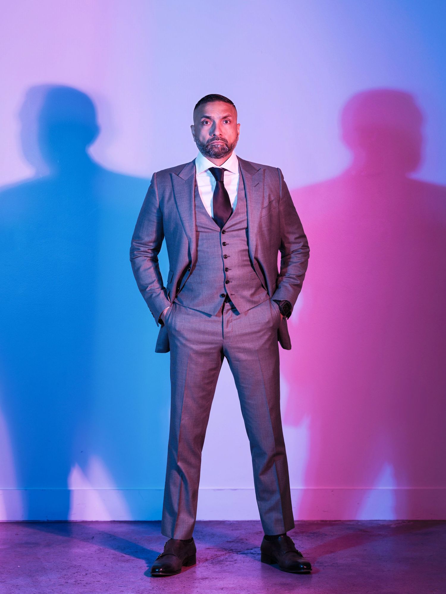 Professional portrait with dramatic pink and blue lighting against a colorful gradient backdrop.