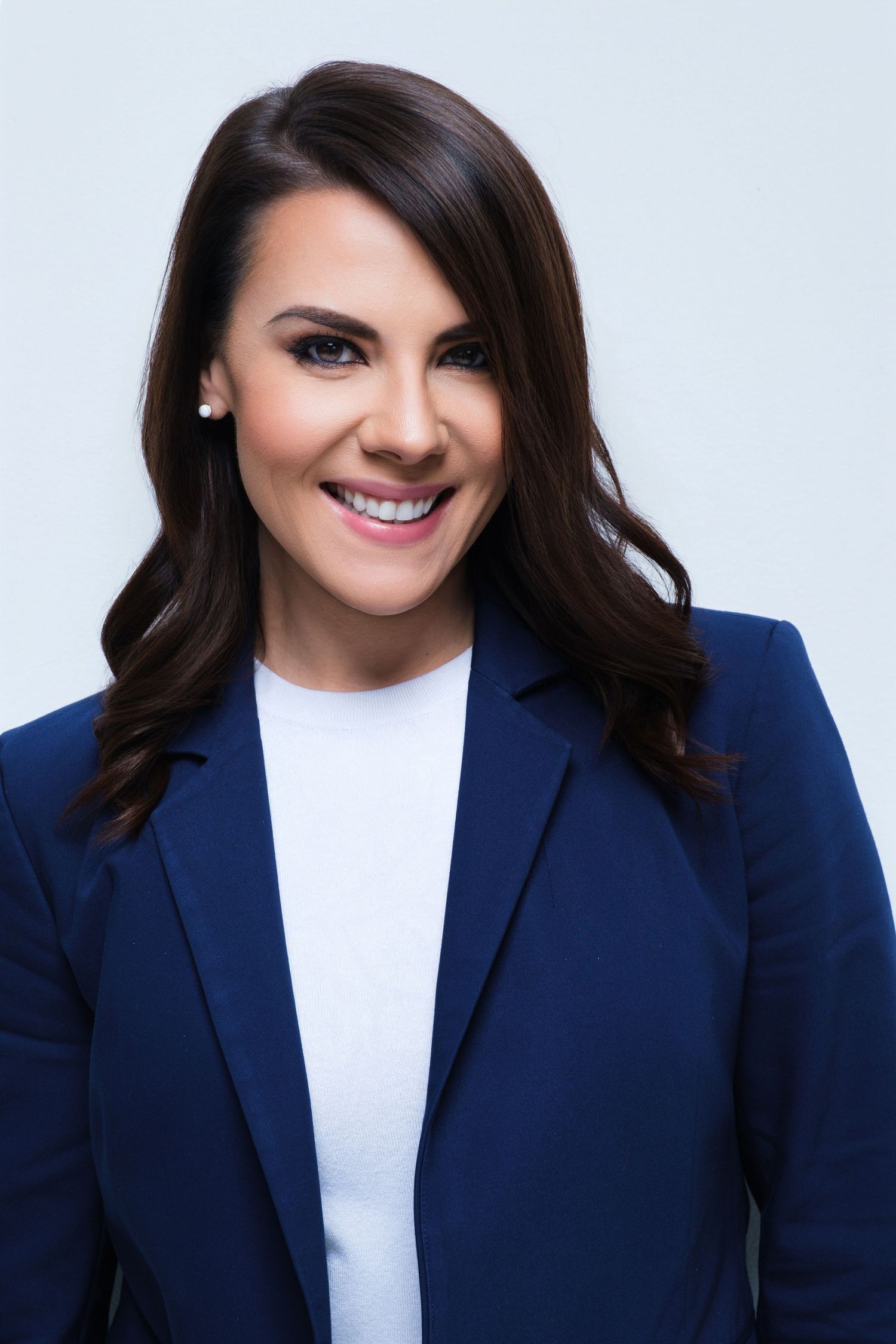 Professional studio portraits in navy blazer and white top against light background.