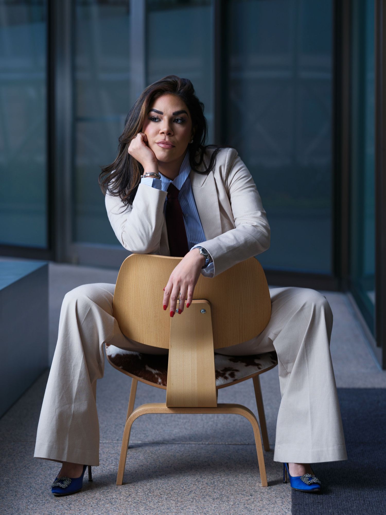 A person in a white blazer poses on a wooden chair in four different artistic positions against a dark background.