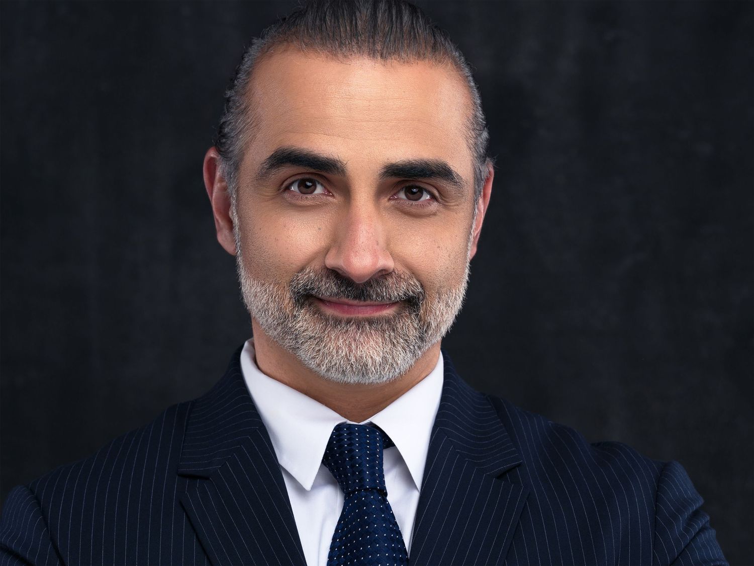A sequence of headshots from left to right shows someone in a navy pinstripe suit with a white shirt and blue tie.