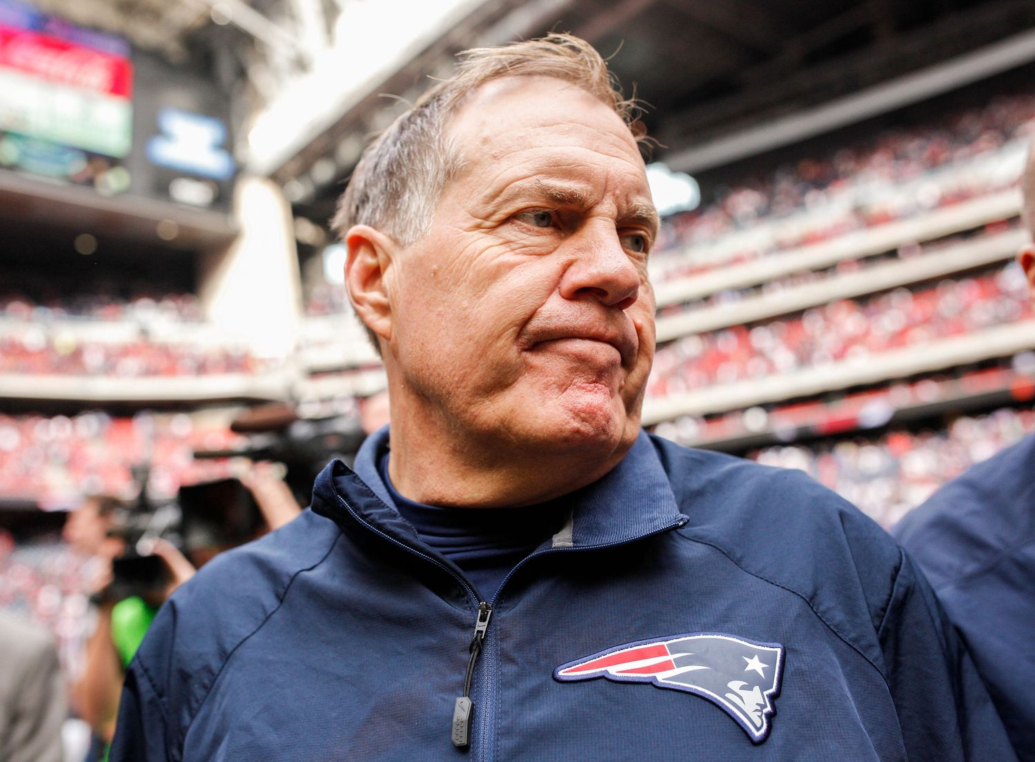 Head coach on sideline during NFL game at packed stadium.