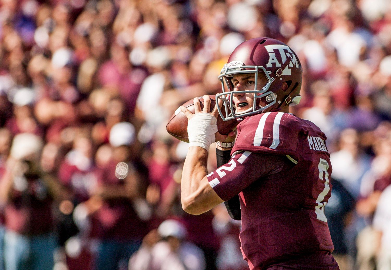 College football players celebrate and throw arms up during a game.