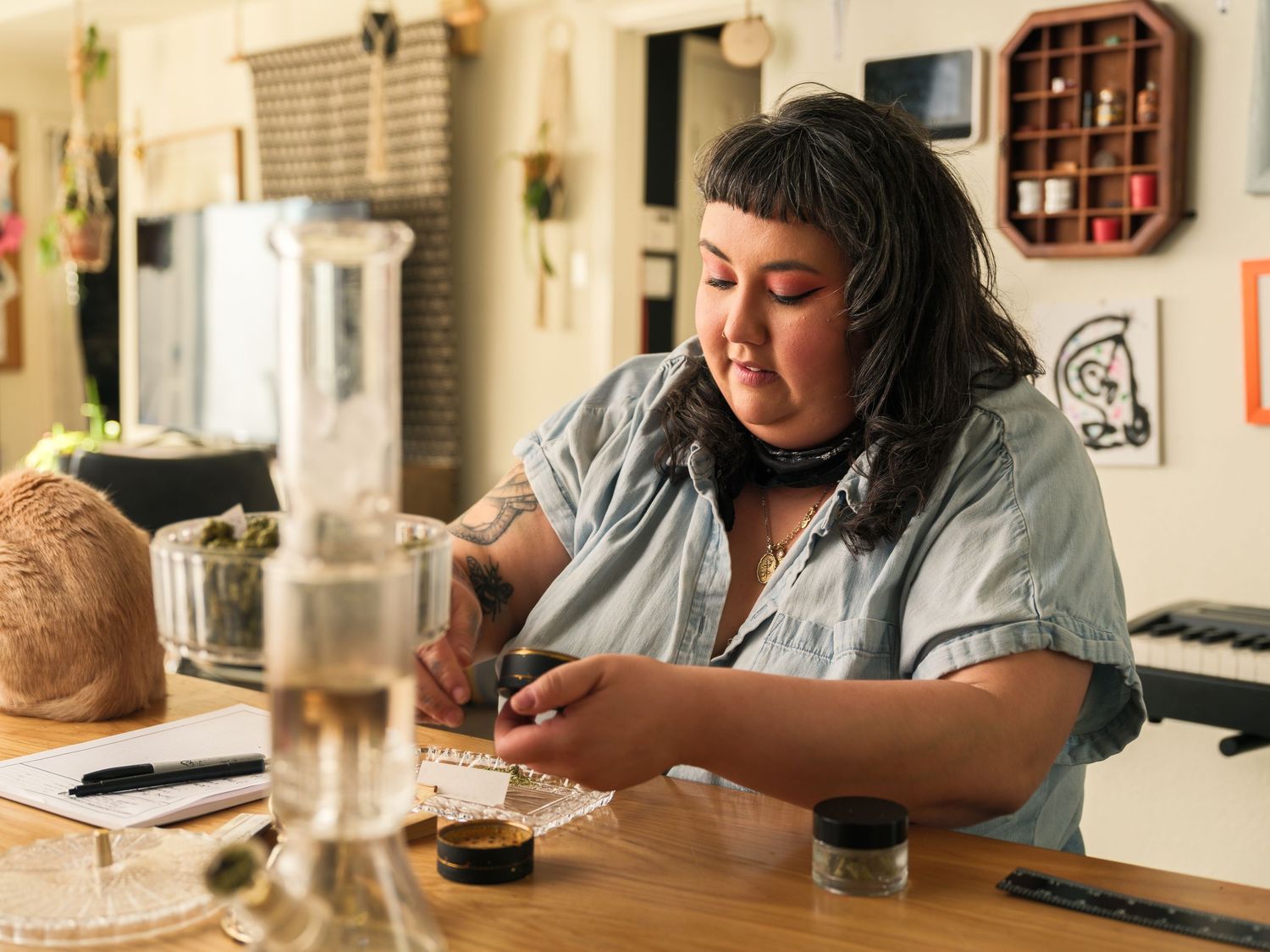 Person working with coffee equipment and glassware on a wooden counter with a bright interior.