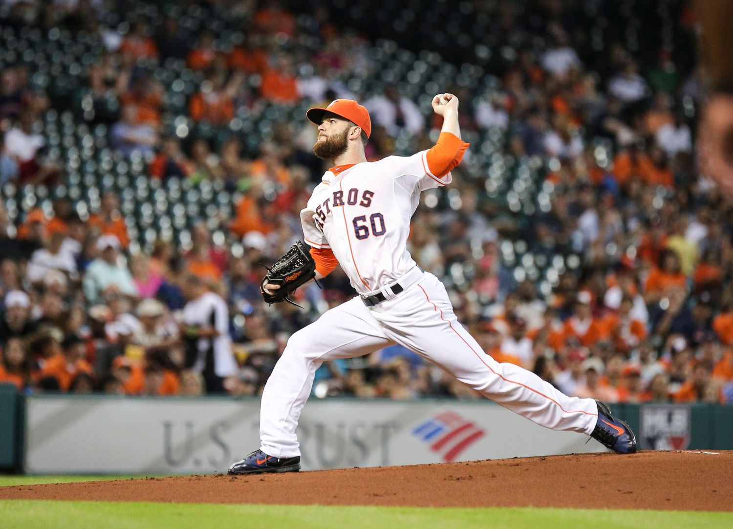 Baseball player makes a diving catch in an orange uniform during a game.
