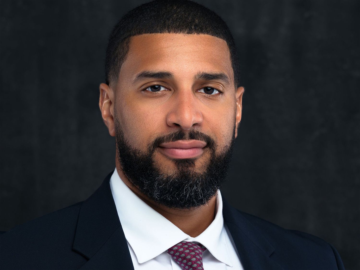 Professional headshot portraits of people wearing business attire against dark backgrounds.