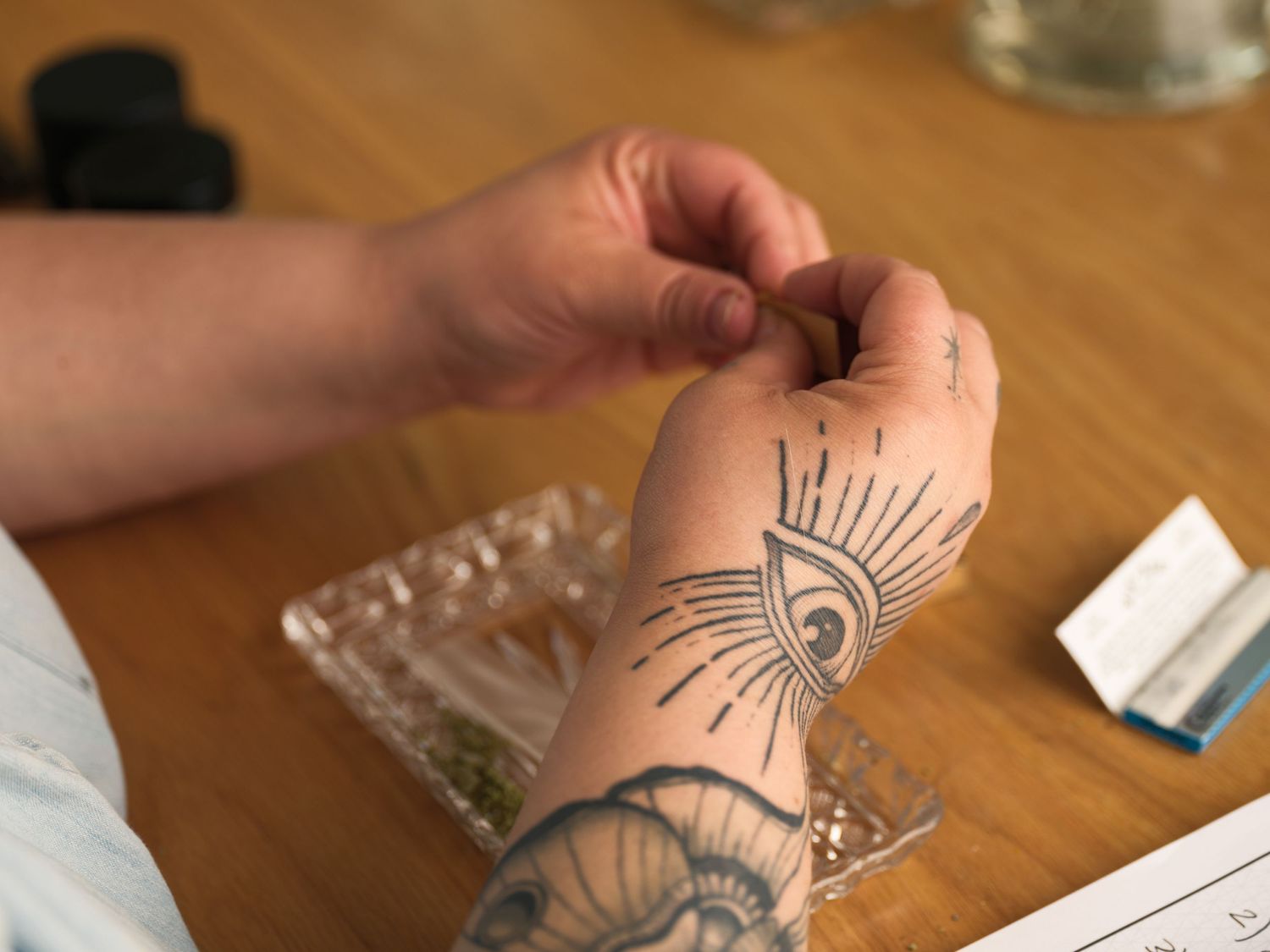 Close-up of tattooed hands with geometric sun design on forearm.