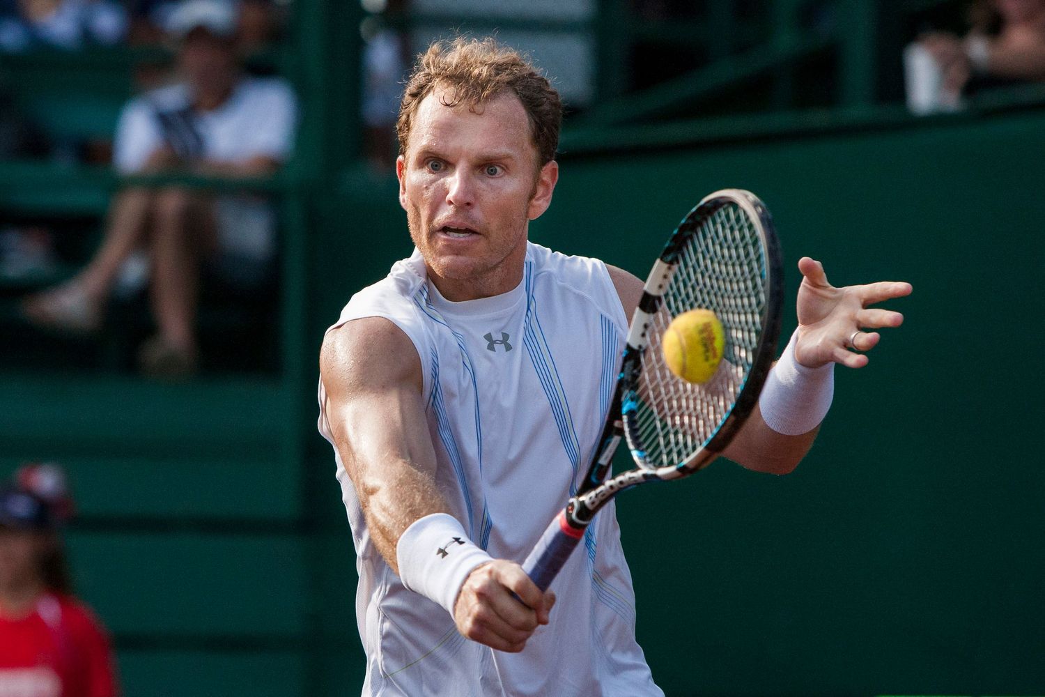 Tennis players return shots on a green court during a competitive match.