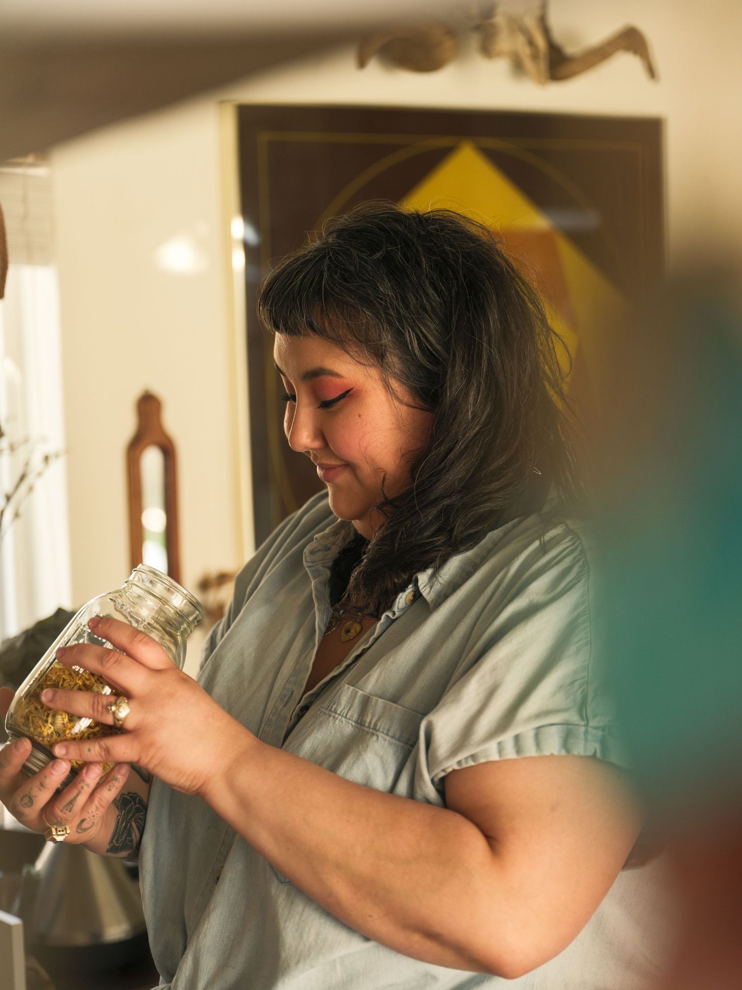 Someone examines contents of a glass jar in a warmly lit kitchen setting.
