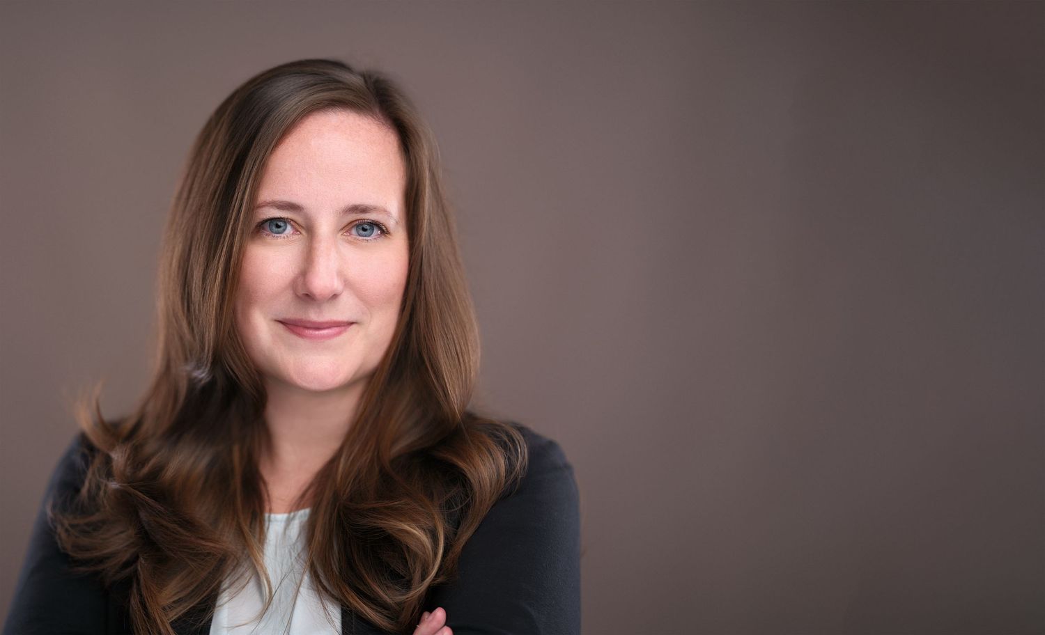 Professional headshot series with warm lighting and brown backdrop.