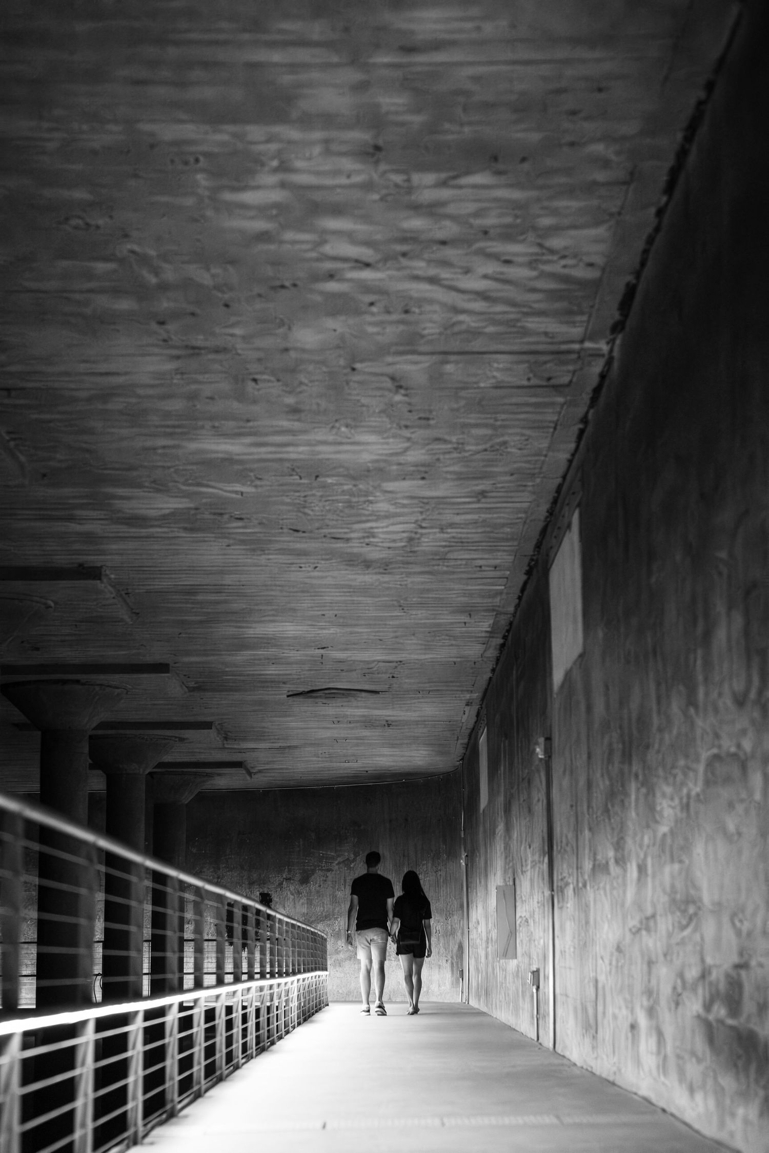 Long concrete tunnel corridor with silhouetted figures in the distance.