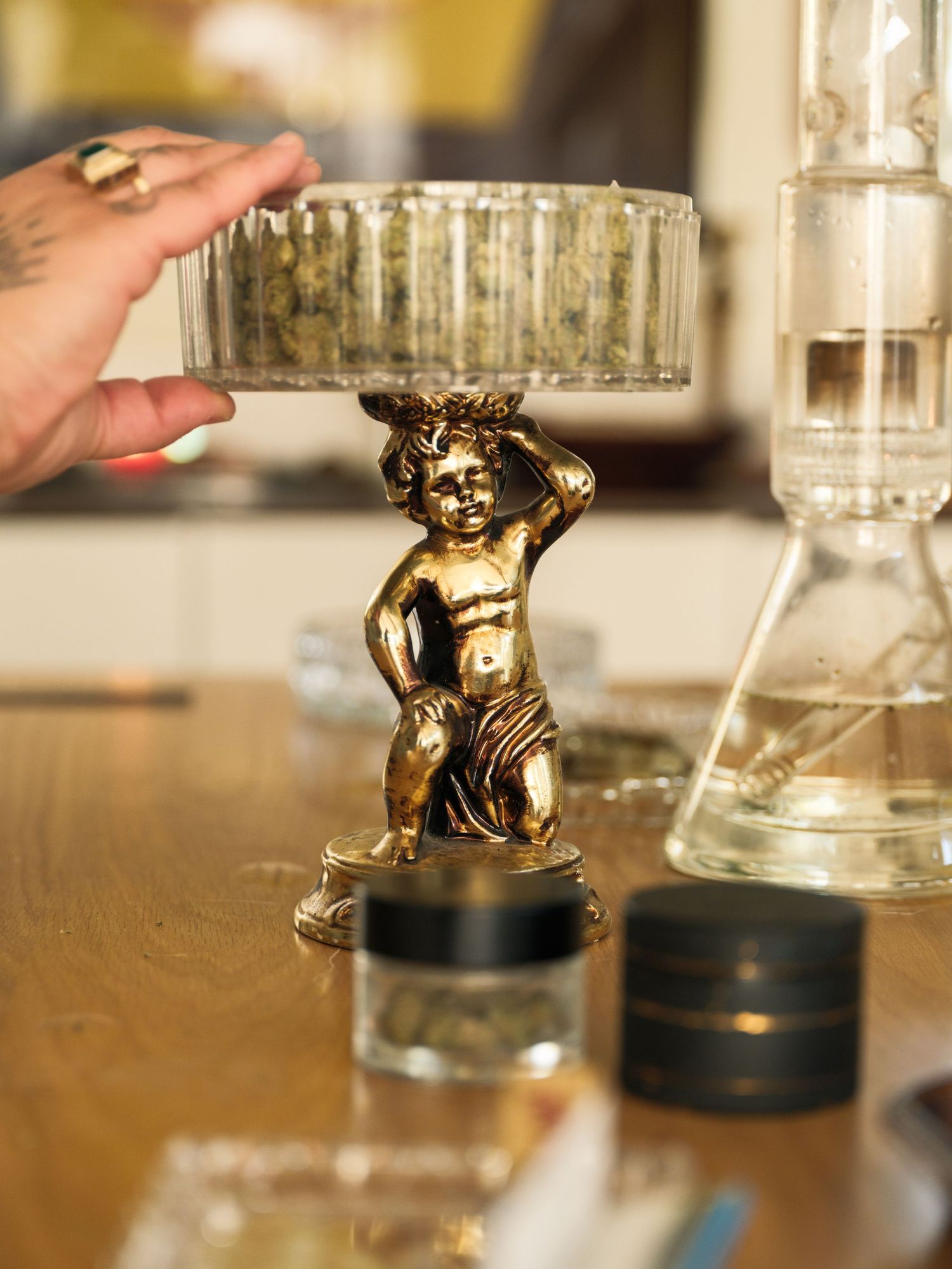 Gold cherub figurine displayed next to glass laboratory equipment on wooden surface.