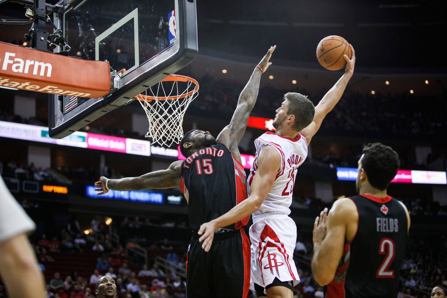 Basketball player attempts a slam dunk during NBA game while defender tries to block the shot.