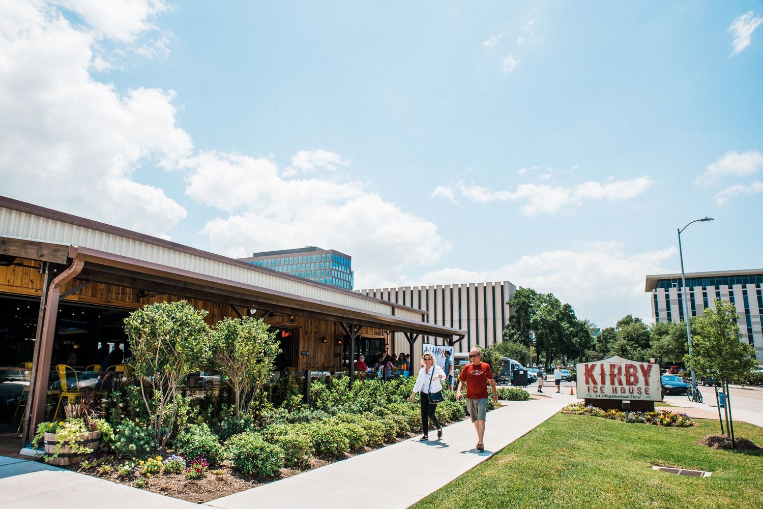 Modern campus buildings and walkway with students strolling under sunny blue sky.
