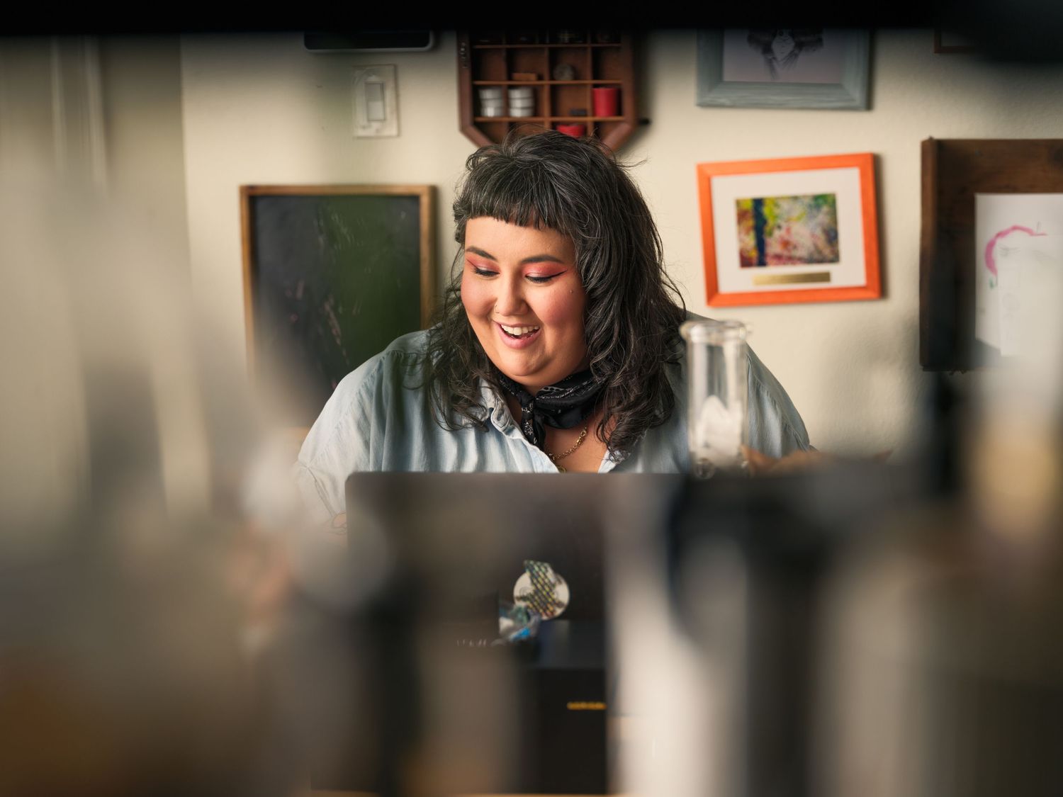 A person prepares to work with coffee brewing equipment and glass containers in a home workspace.