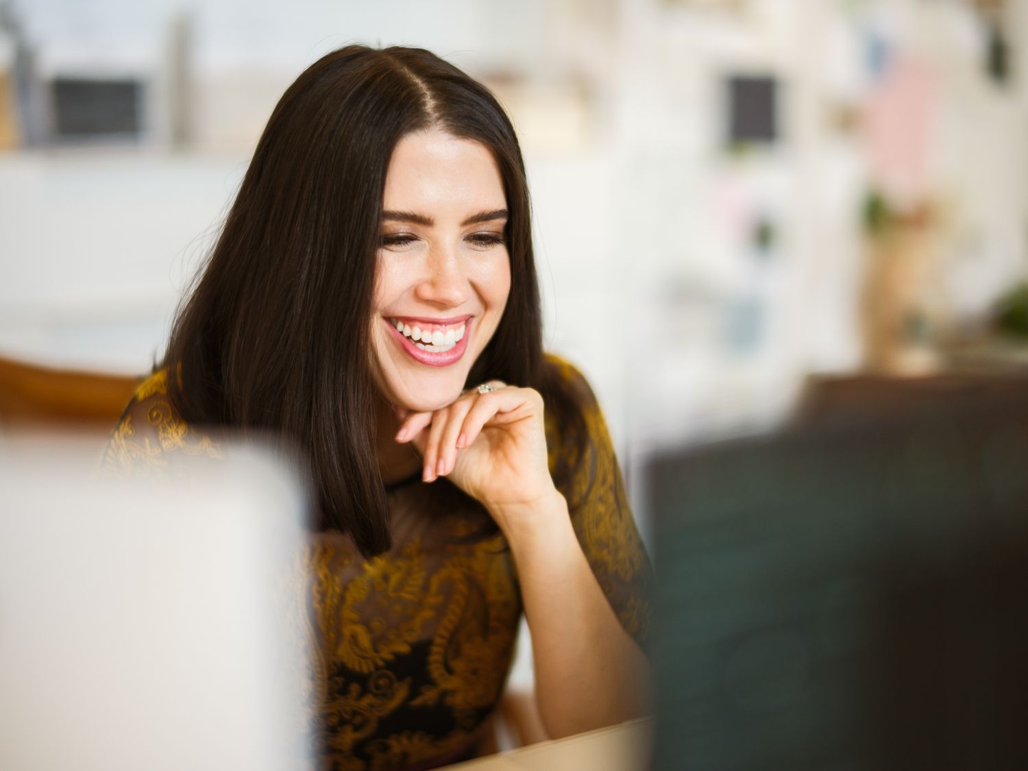 A person smiles warmly while sitting with a relaxed demeanor in a casual indoor setting.