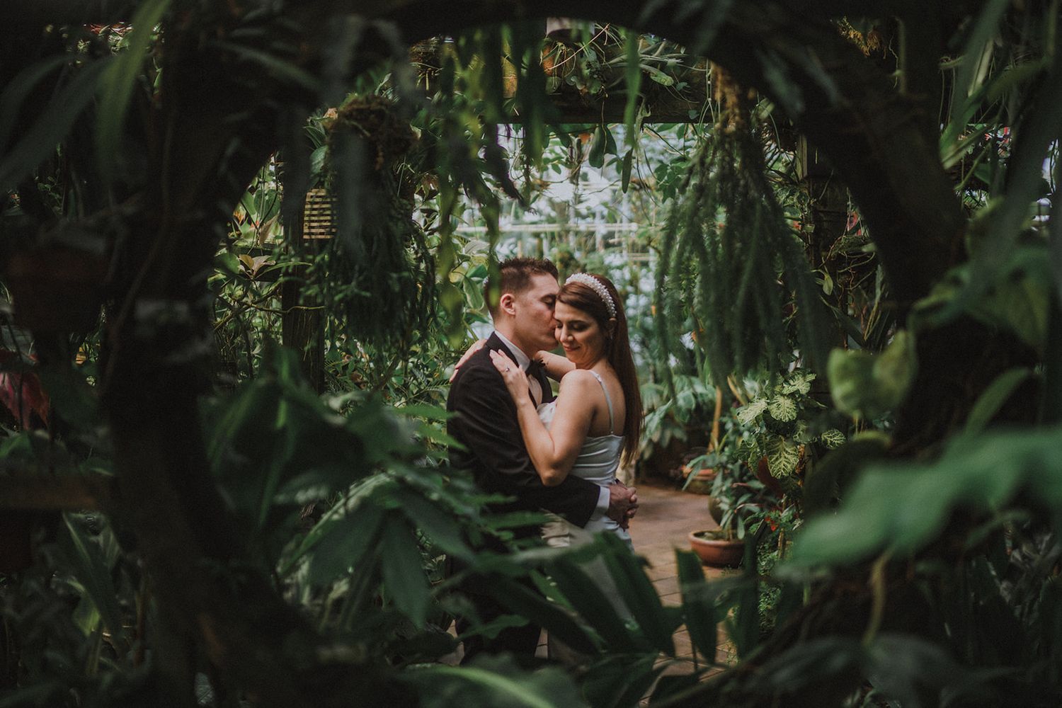 Romantic greenhouse wedding setting with lush tropical plants and natural lighting.