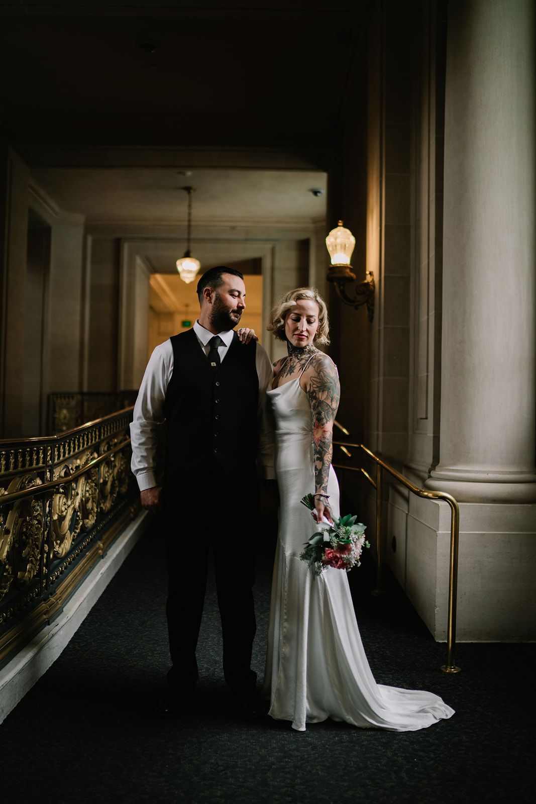 Elegant wedding portraits in a dimly lit historic hallway with classic architectural details.