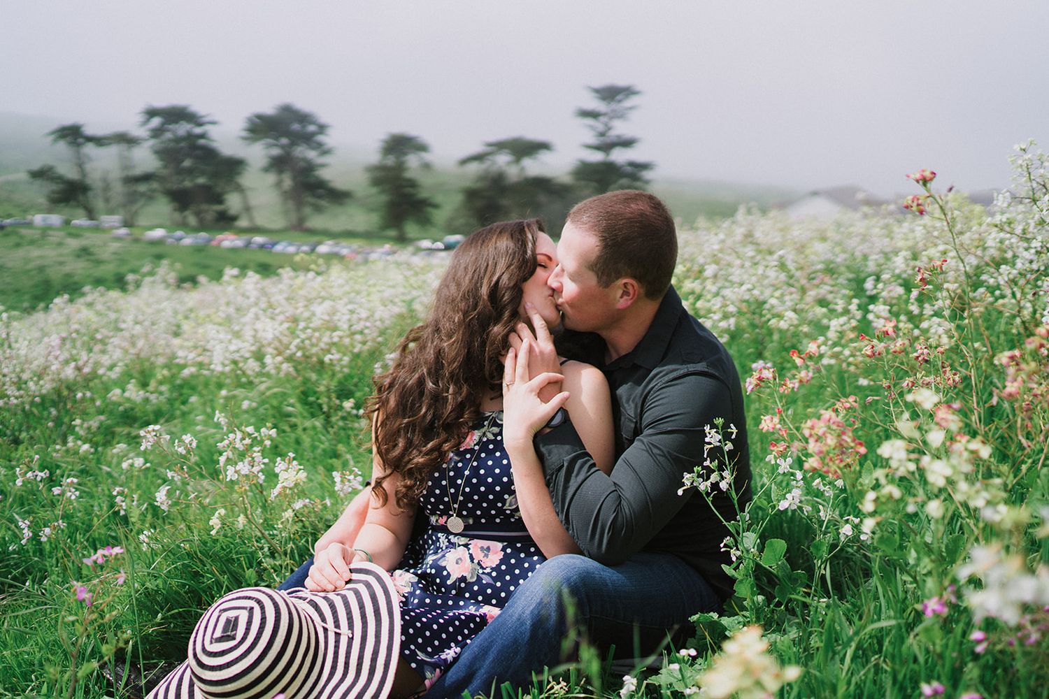 A couple shares an intimate moment in a wildflower meadow during golden hour.