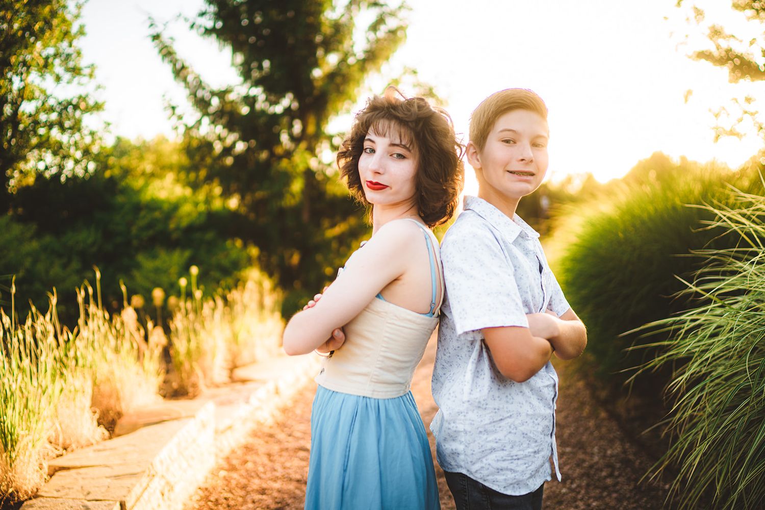 Family members pose together on a nature path during golden hour with sunlit foliage.