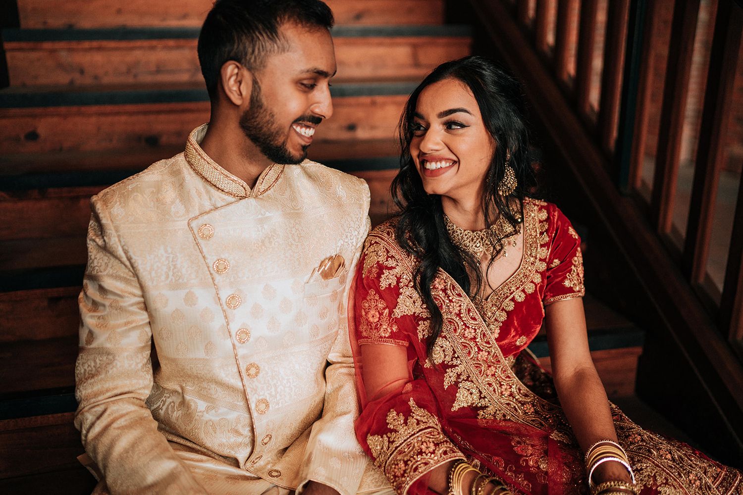 Traditional Indian wedding couple in elegant red and cream attire.