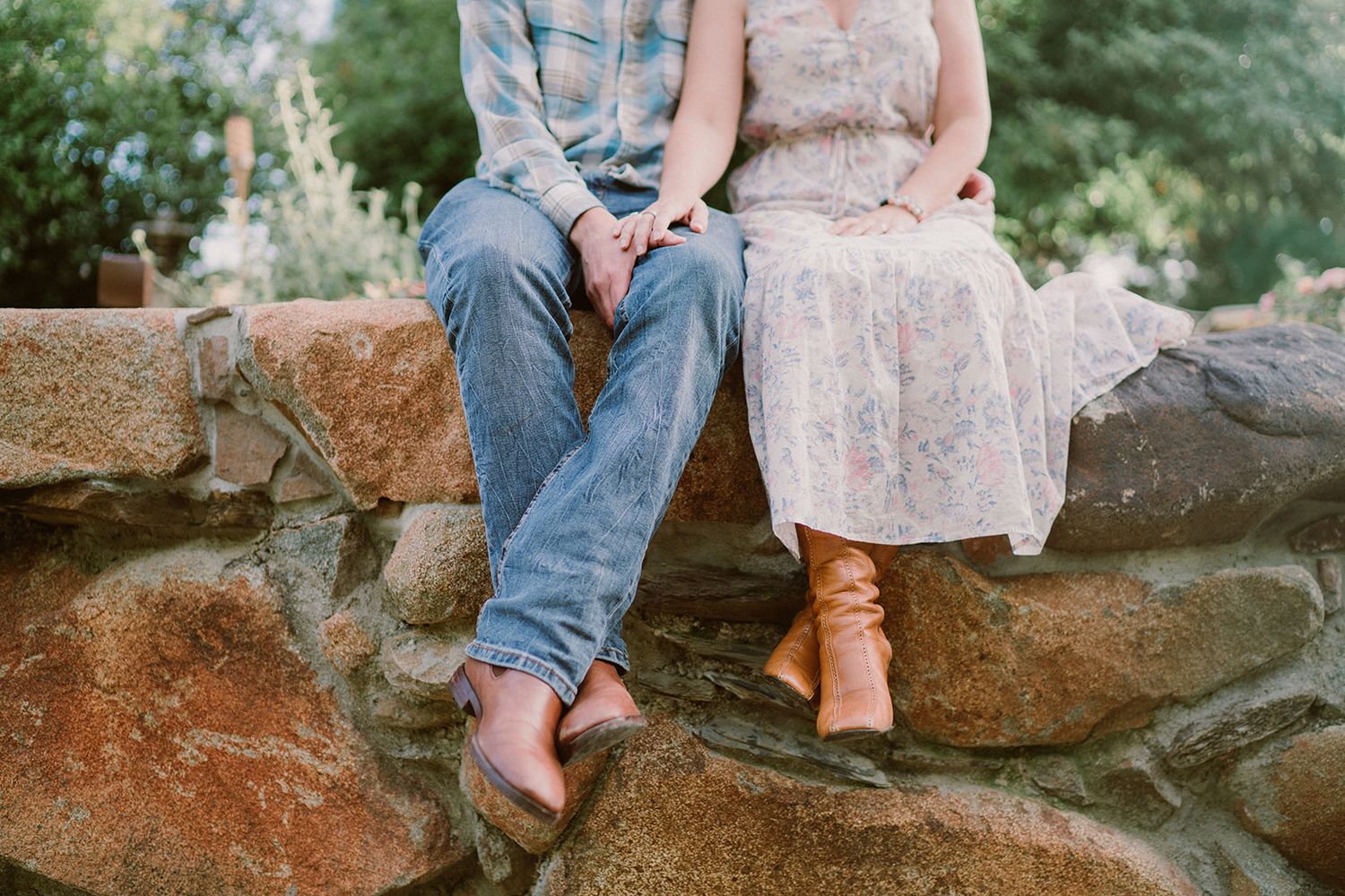 Two people sit casually on large rocks in a natural outdoor setting.