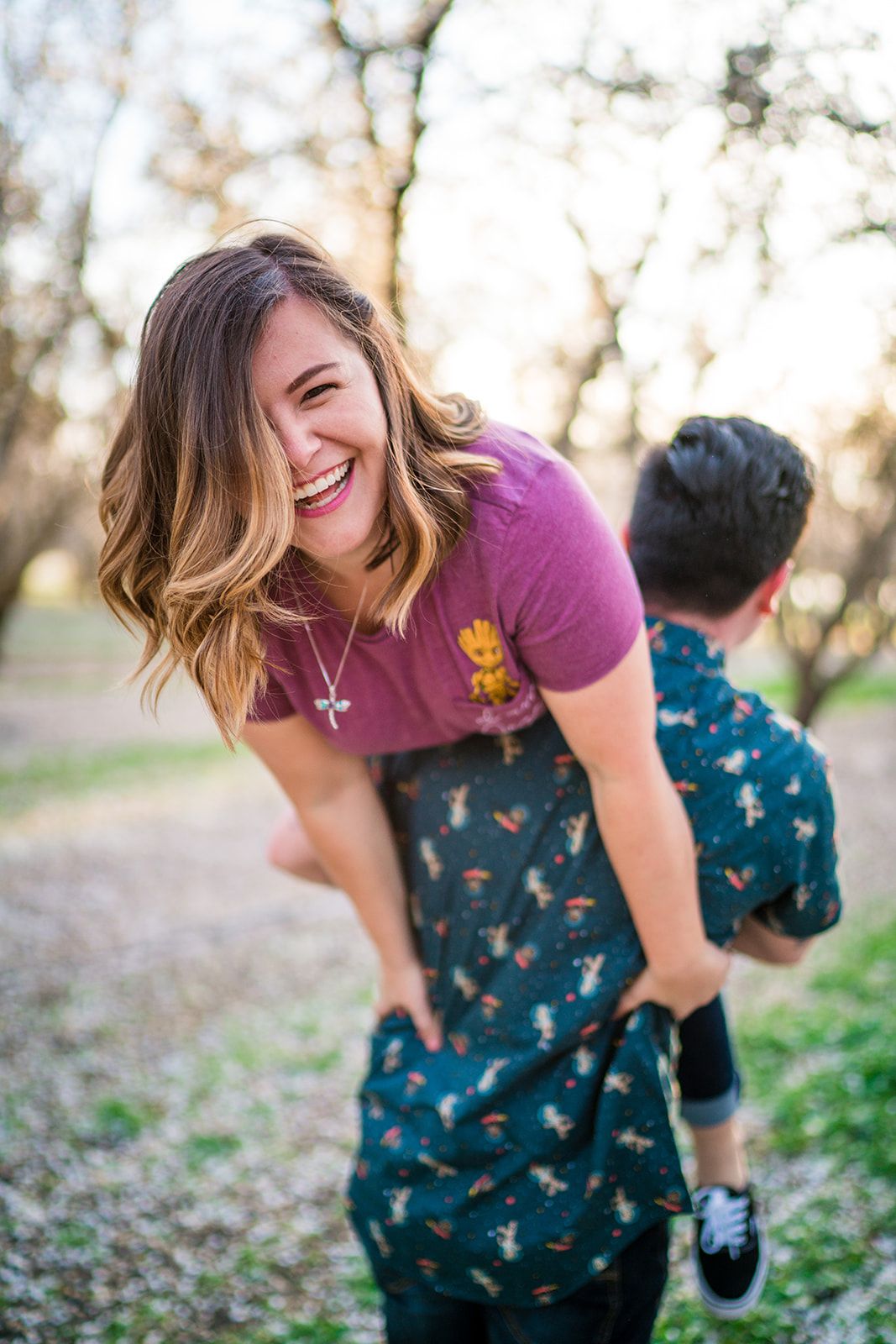 A playful couple laughs together during a casual outdoor photoshoot at sunset.