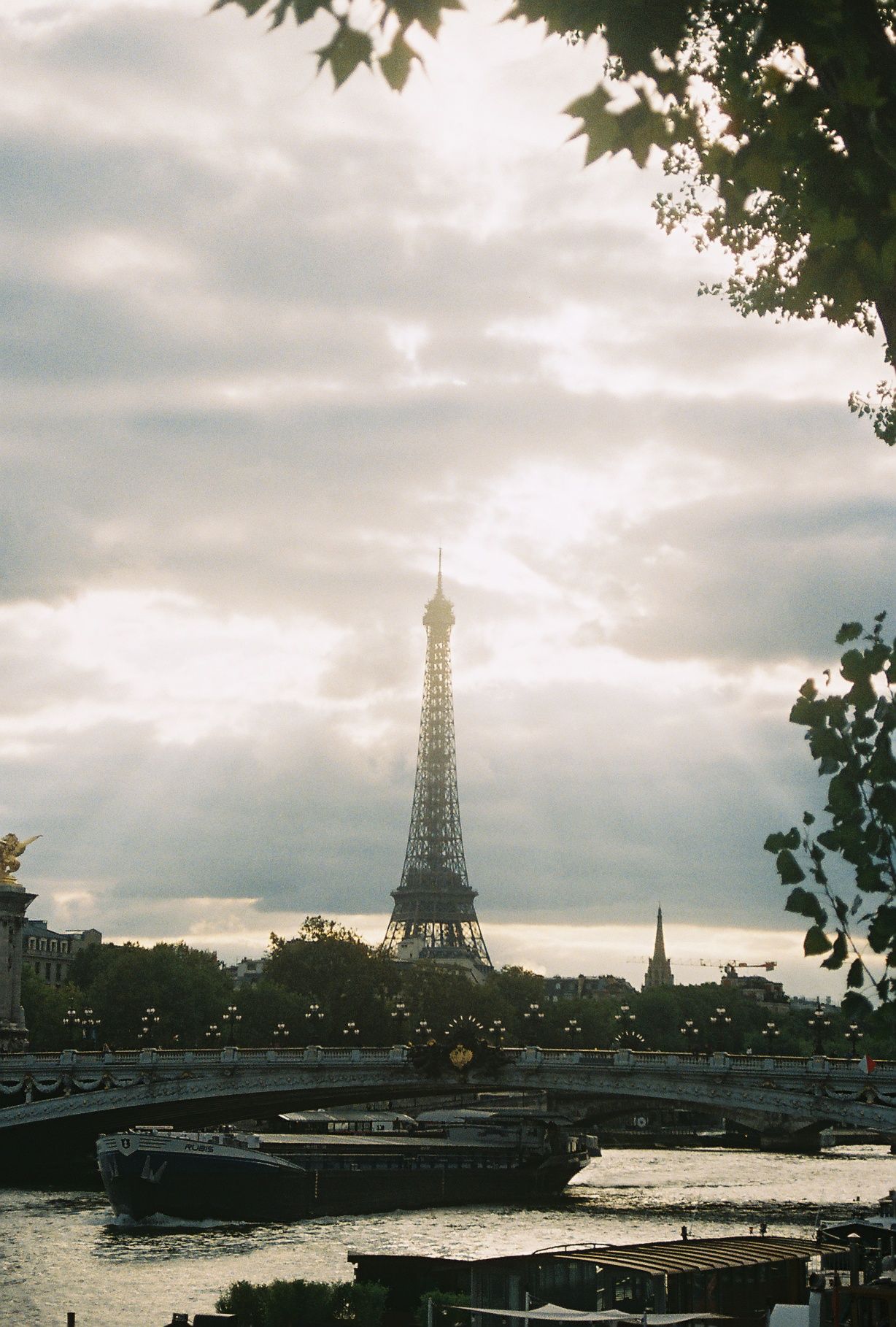 Panoramic series of five moody photographs showing the Eiffel Tower and Seine River in Paris under cloudy skies.