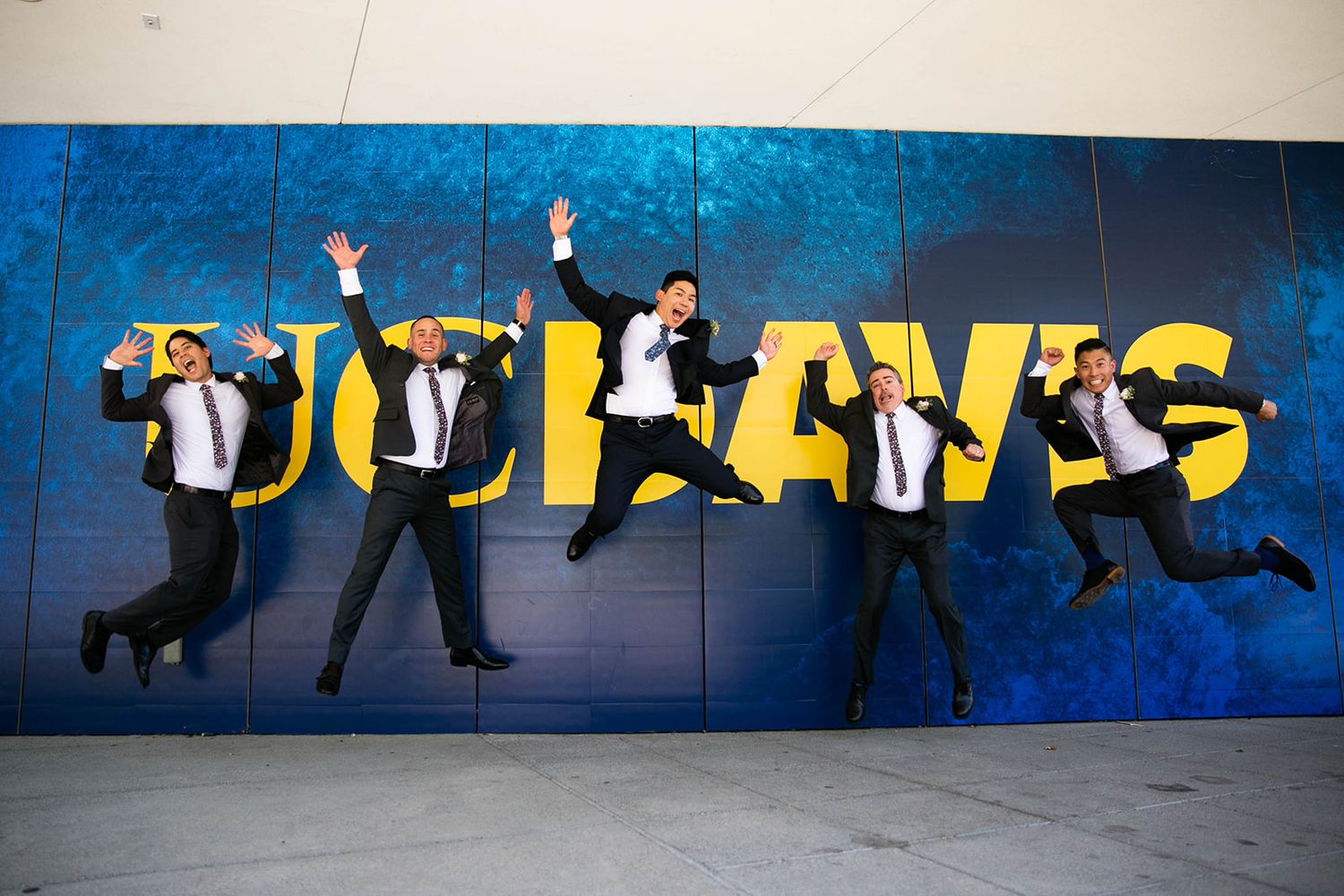 Wedding party posing playfully against a blue wall with graffiti art.