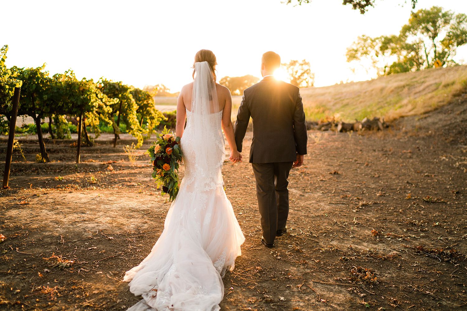 Golden hour wedding portraits with couple walking through scenic outdoor location.