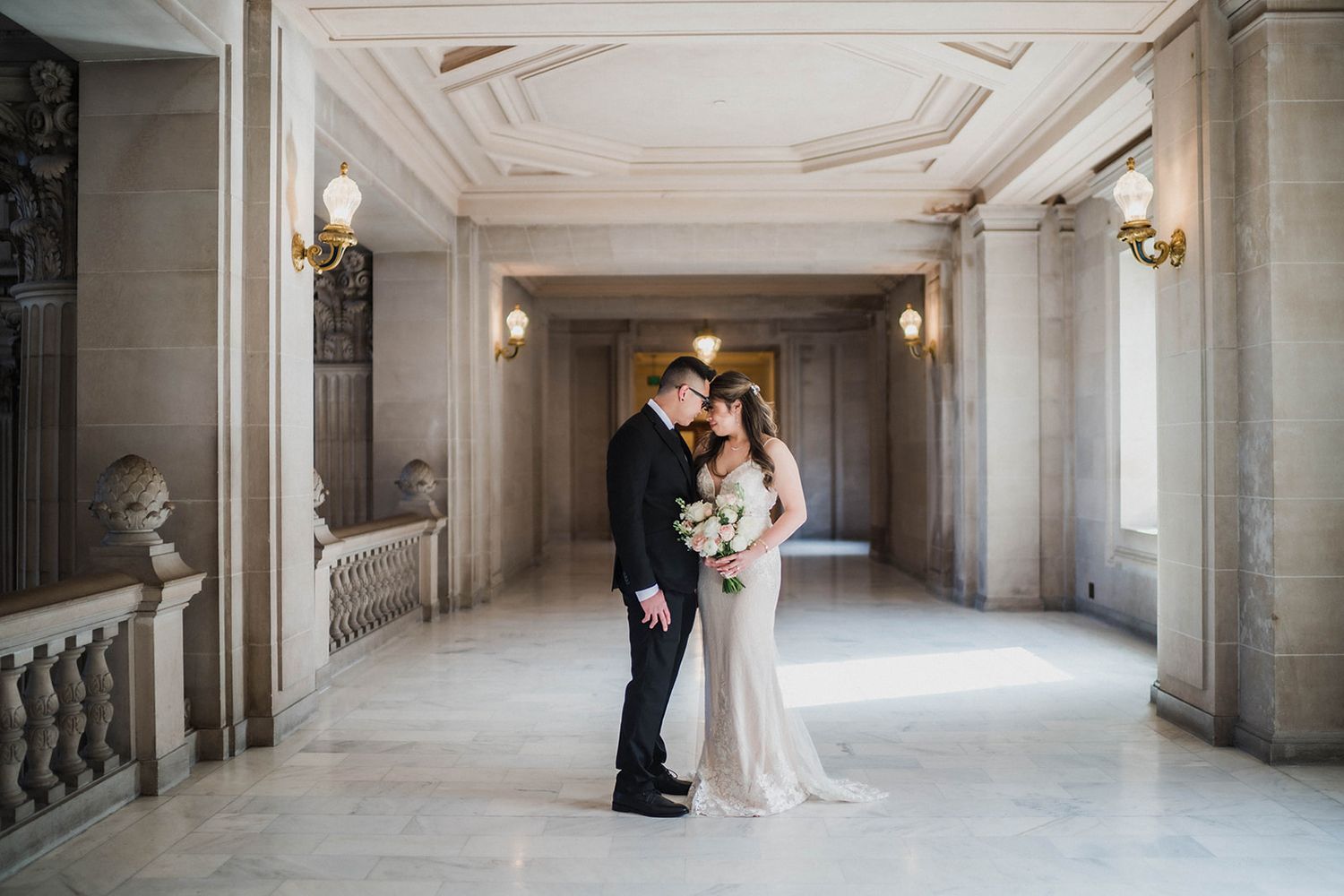 Elegant wedding photos taken in a classic marble hallway with grand architecture.