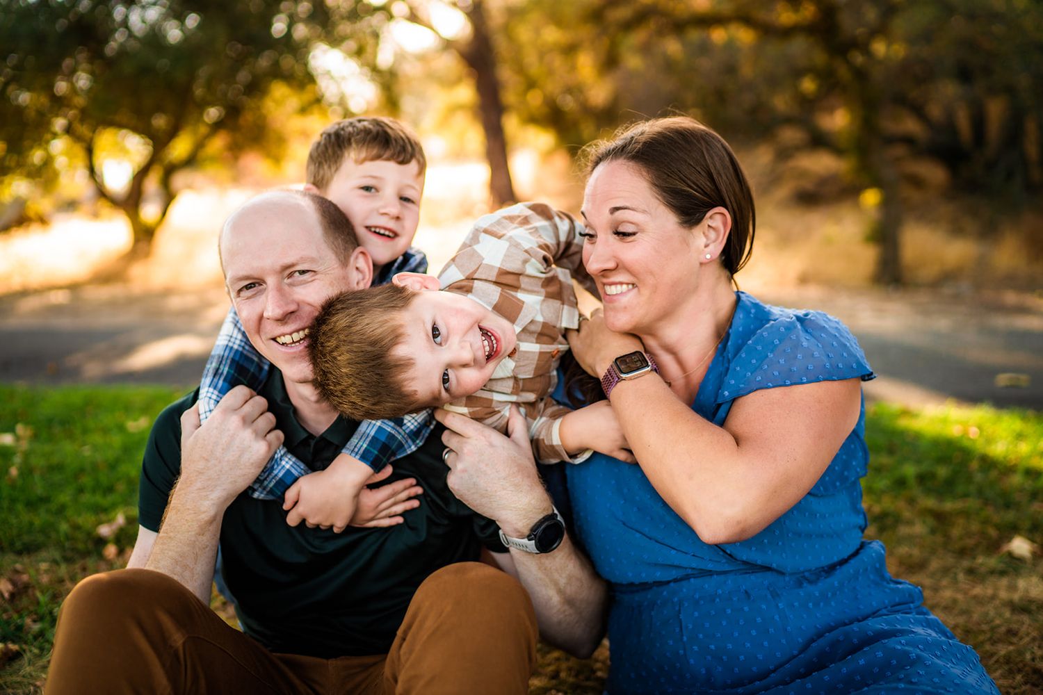Candid family moments captured on grass during a playful outdoor photo session.