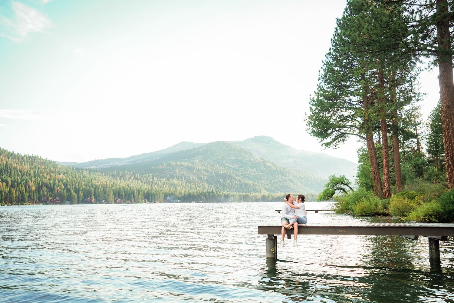 Scenic lake view with mountain backdrop and wooden dock extending into calm waters.