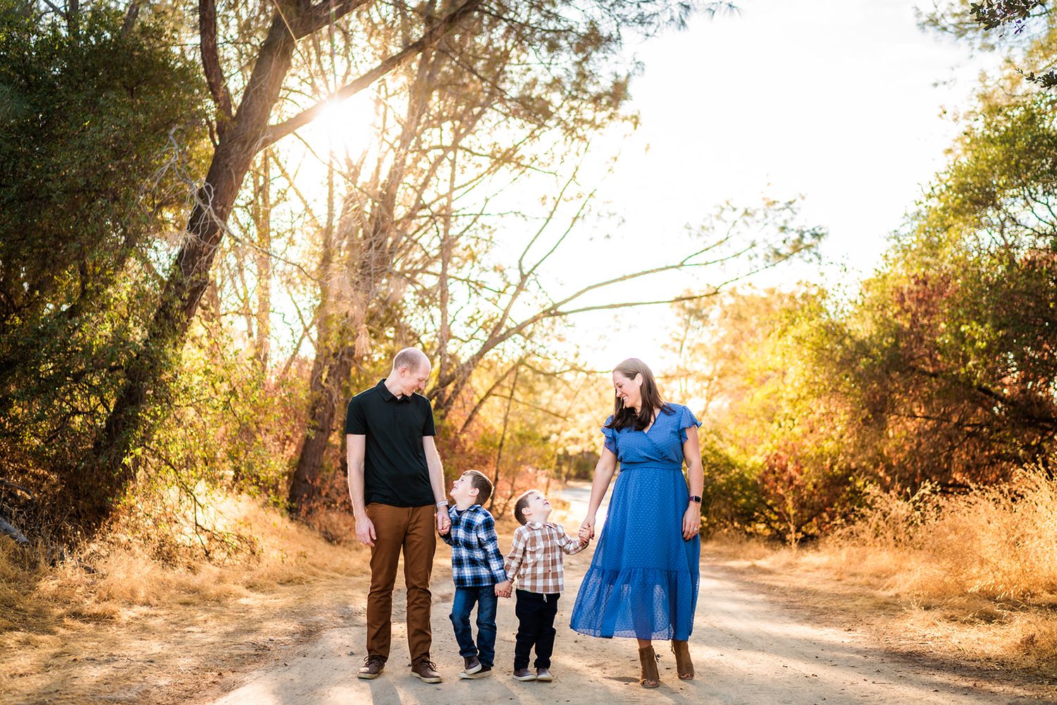 Family enjoying a golden sunset walk along a tree-lined dirt path on a warm autumn evening.