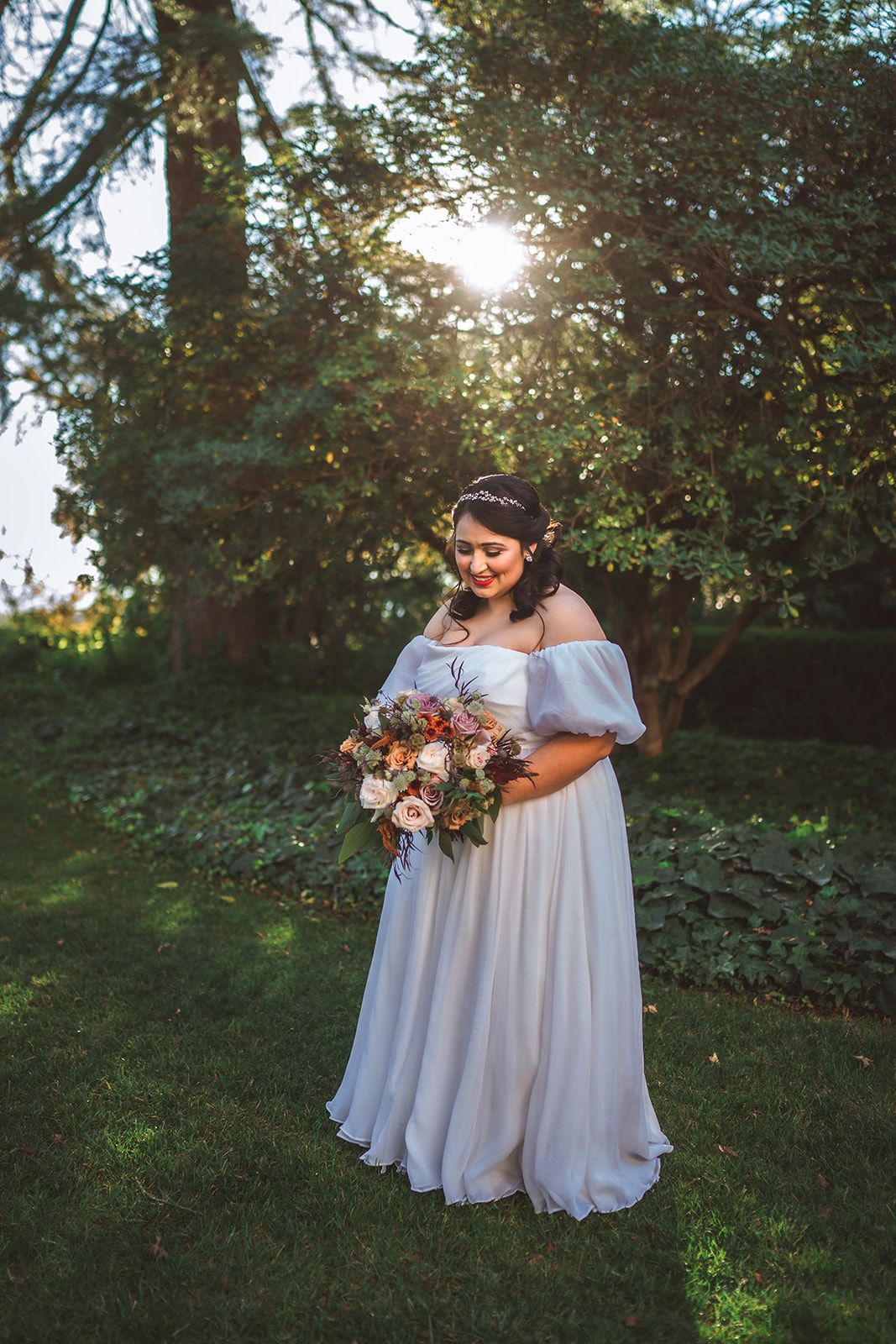 Wedding portraits in soft natural light under trees with flowing white dresses.