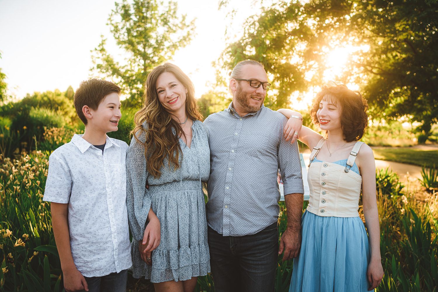 A sunset family photoshoot with golden light streaming through trees in the background.