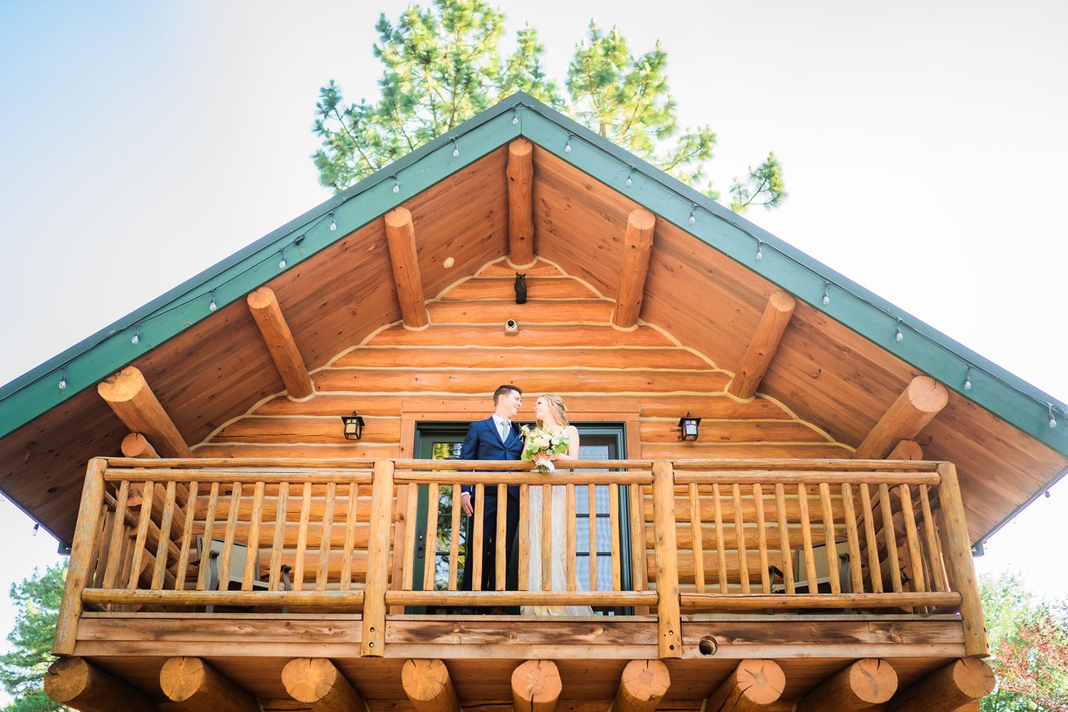 Wooden cabin with rustic architectural details and green trim against blue sky.
