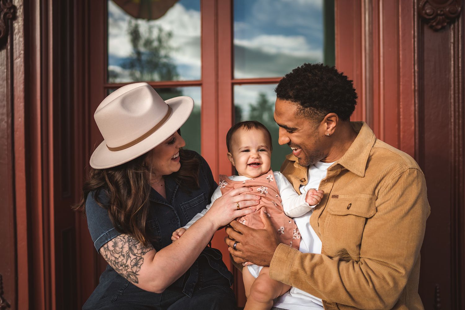 Happy family sharing a joyful moment together by a large window with brown trim in warm lighting.