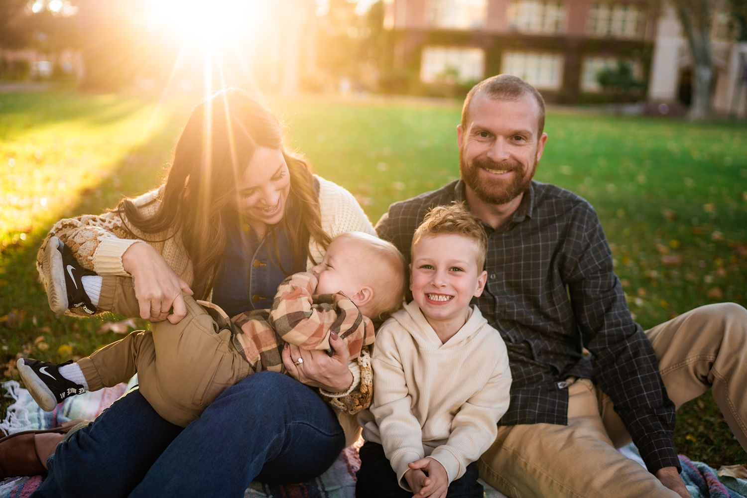 Family shares tender moments with their young child during golden hour outdoor photo session at sunset.