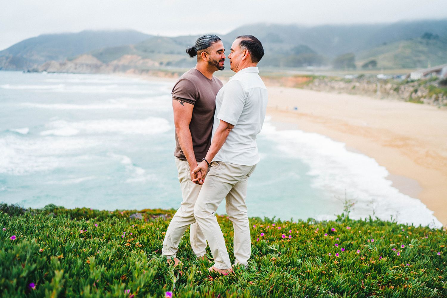Romantic couple embracing on a scenic coastal clifftop at sunset.