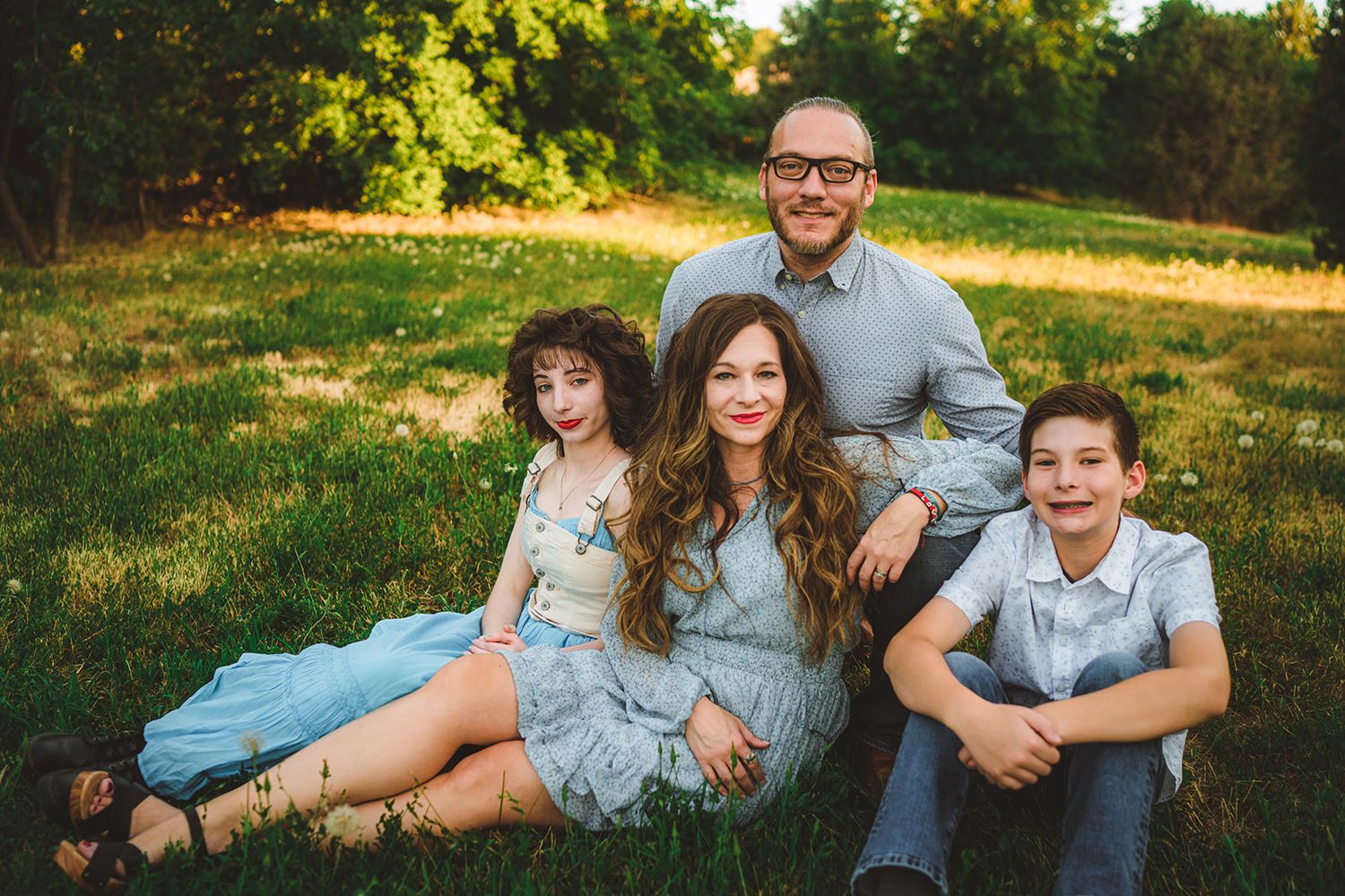 A relaxed family photo session on lush green grass during a summer evening.