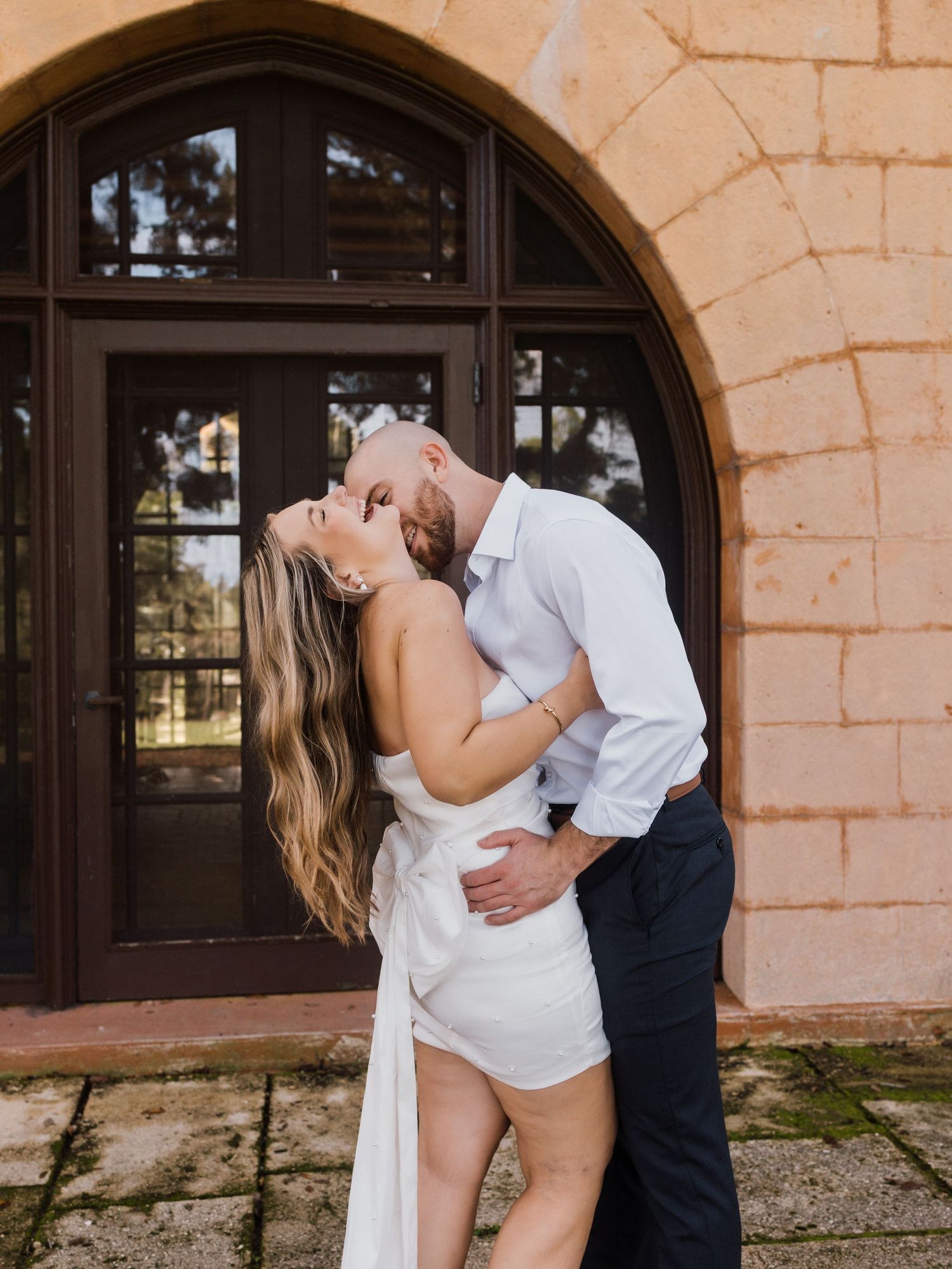 A romantic couple shares intimate moments against a stone wall in a series of dip poses.