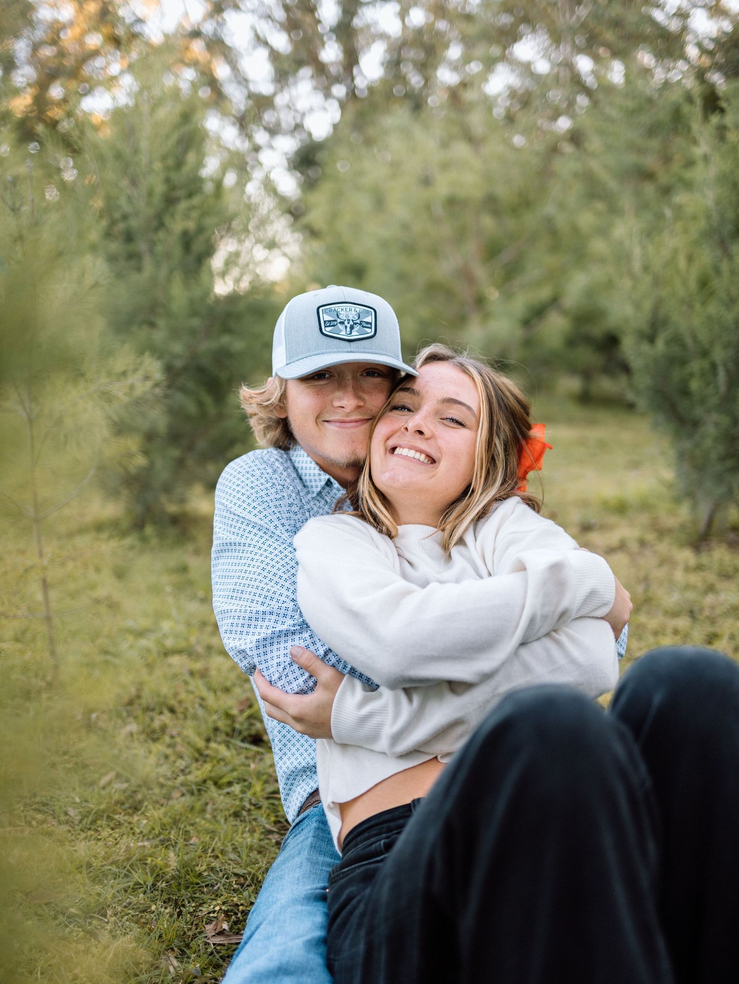 A couple sitting together outdoors sharing a candid moment of laughter and joy in a natural setting.