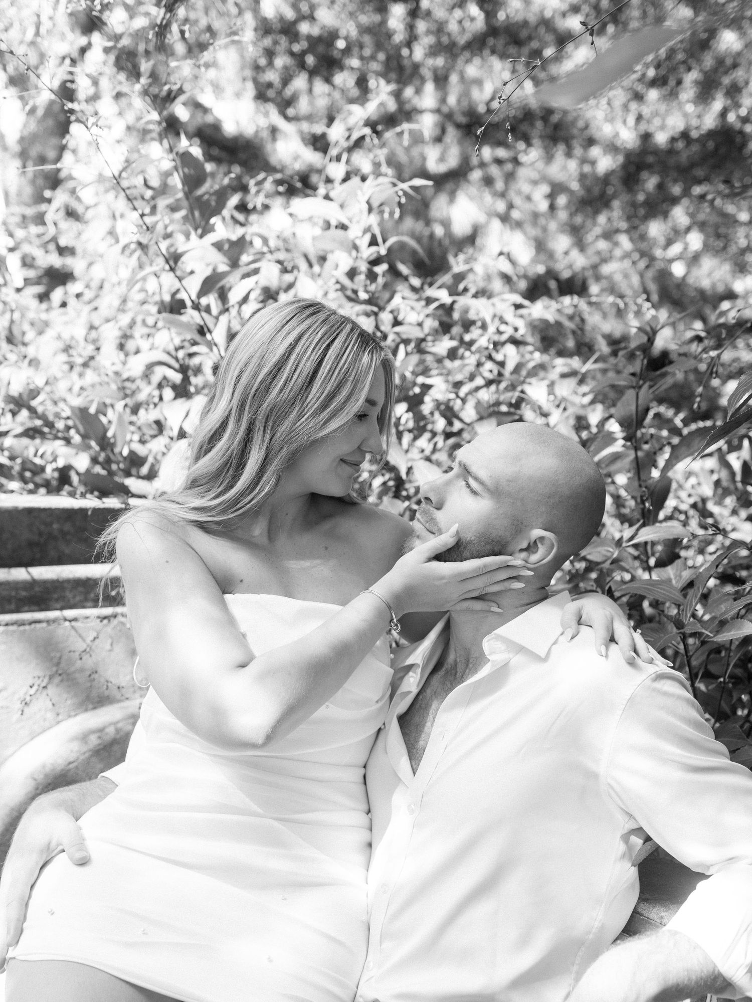 Black and white romantic portrait of couple in elegant attire sharing an intimate moment.