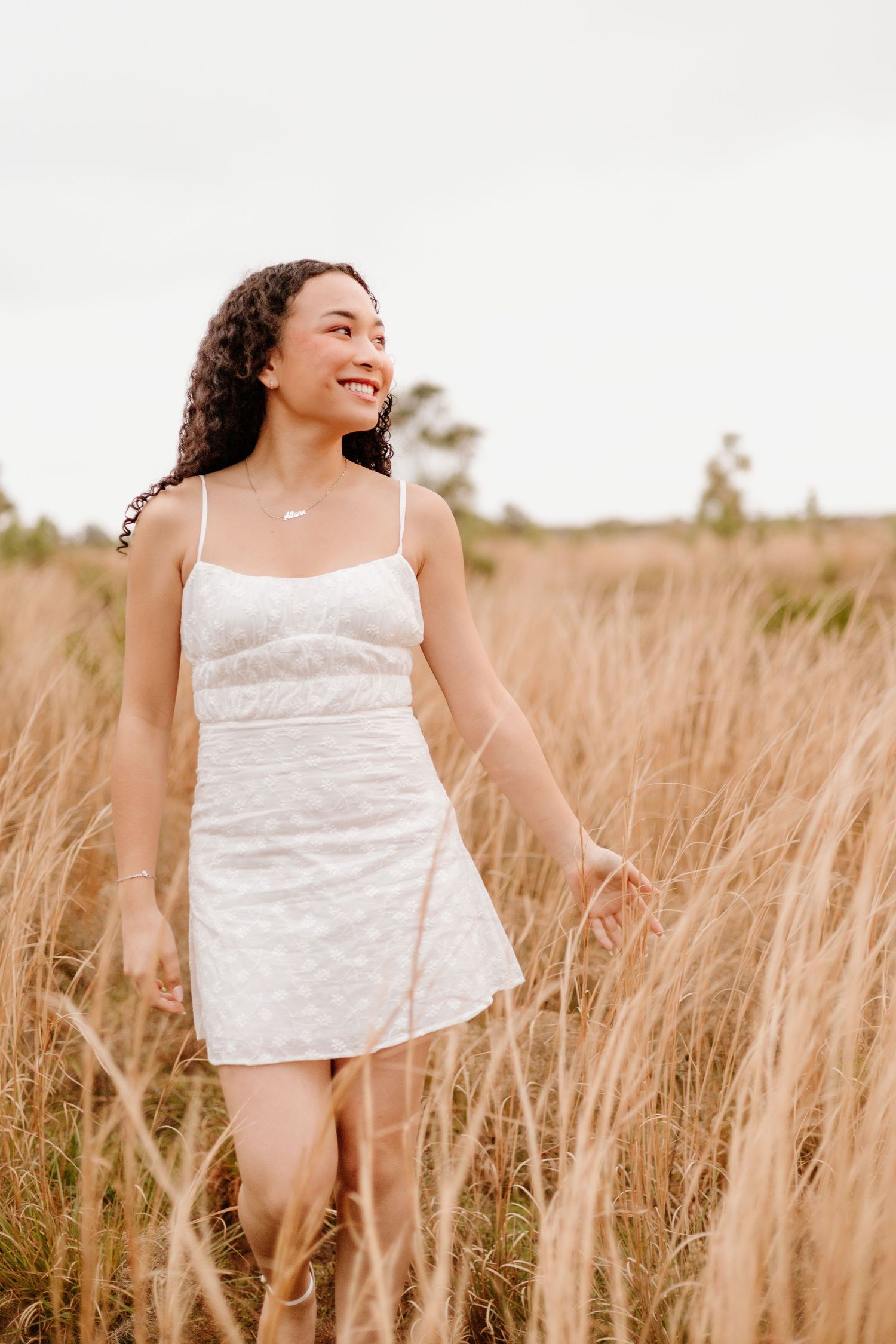 Carefree poses in a summer field wearing white top against golden wheat grass.