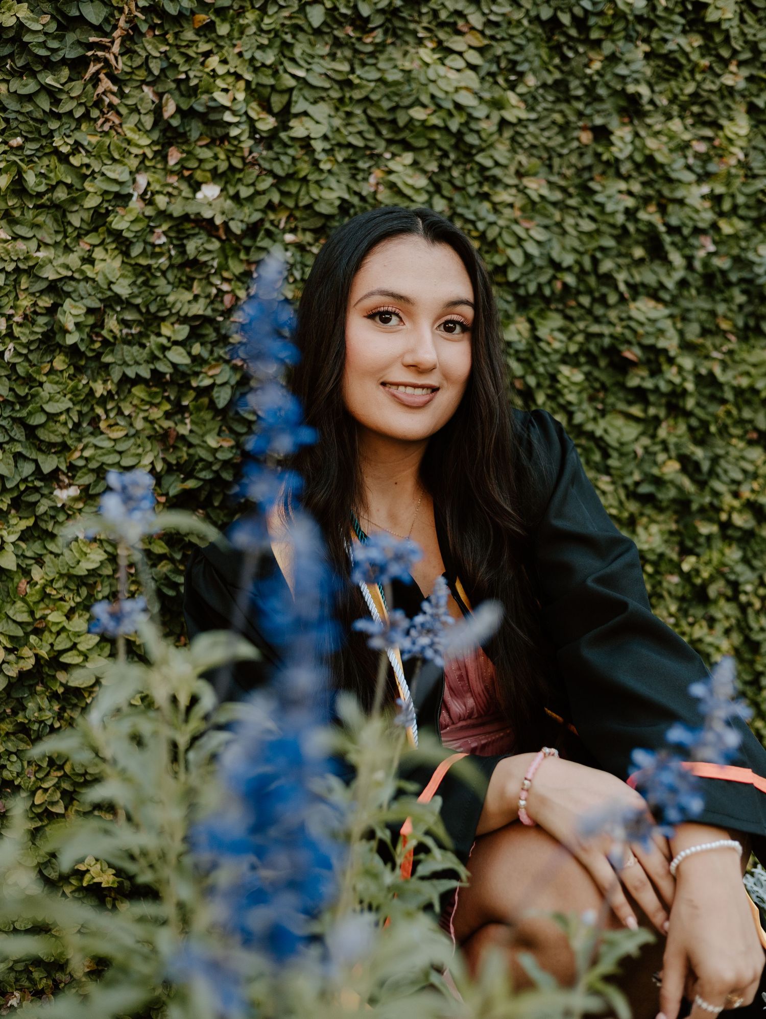 Portrait among ivy and blue flowers with natural garden backdrop.