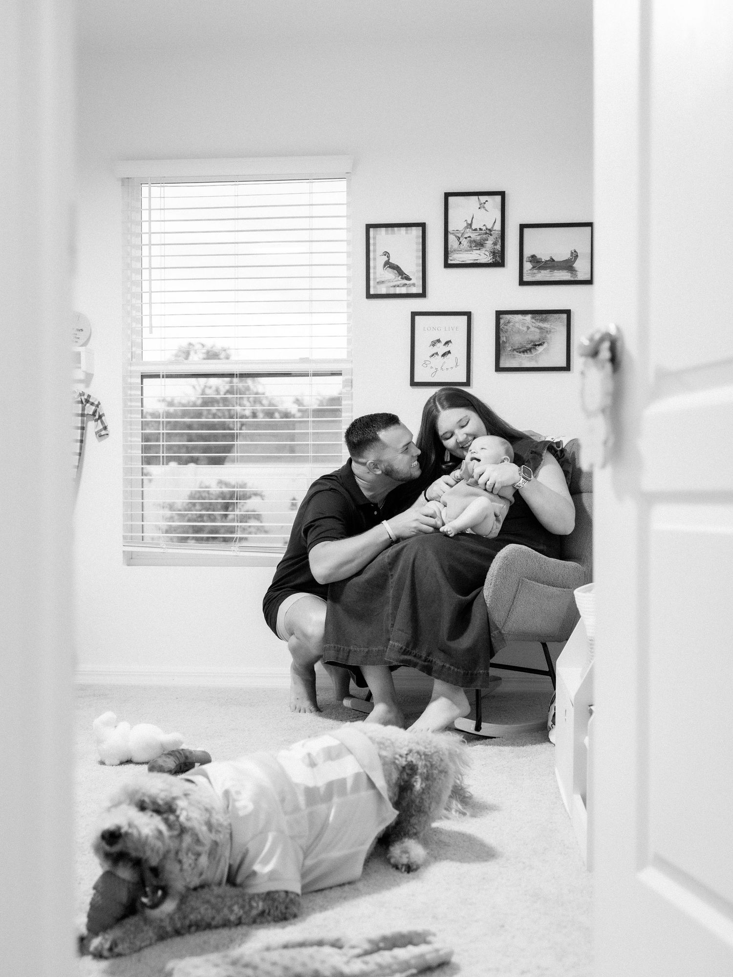 A series of four black and white family photos showing tender moments of affection and play on a couch in a brightly lit room.