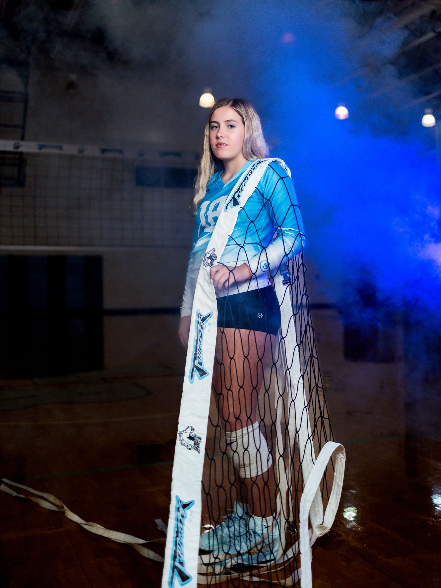 A person wearing an illuminated geometric pattern coat poses in dramatic blue lighting against a dark background.