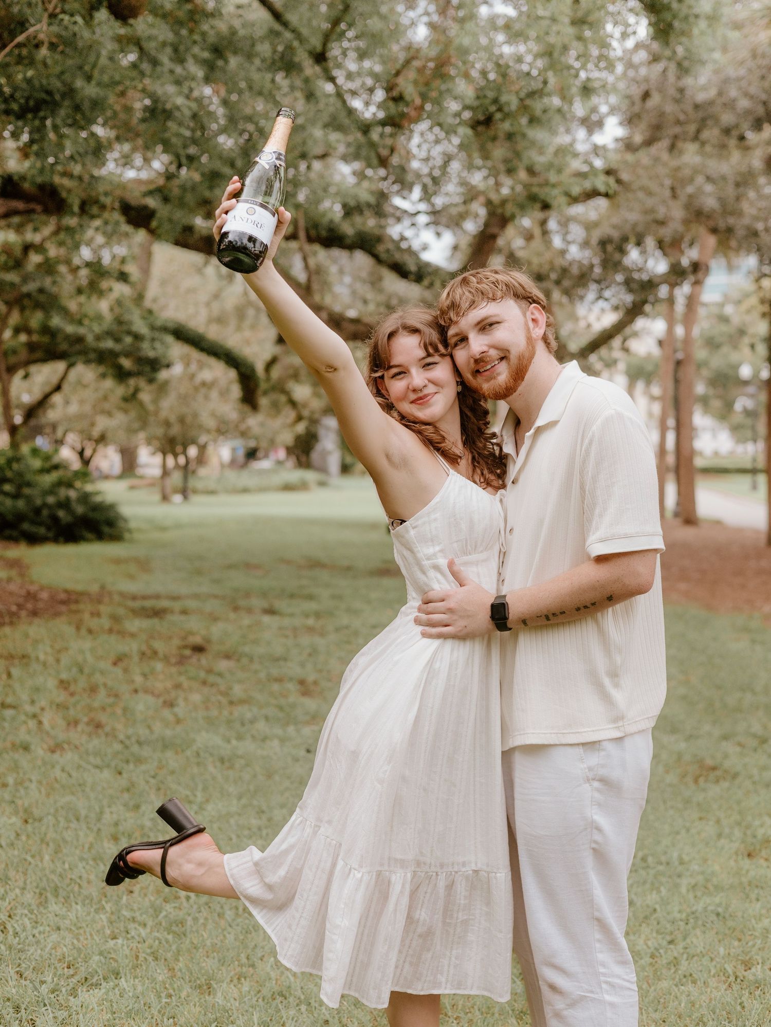 A joyful couple celebrates with champagne in a dreamy outdoor garden setting.