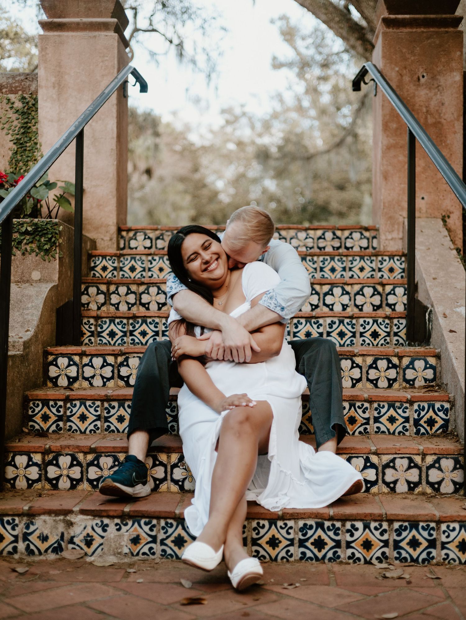 Tender moment captured on ornate tiled stairs with Mediterranean-style architecture.