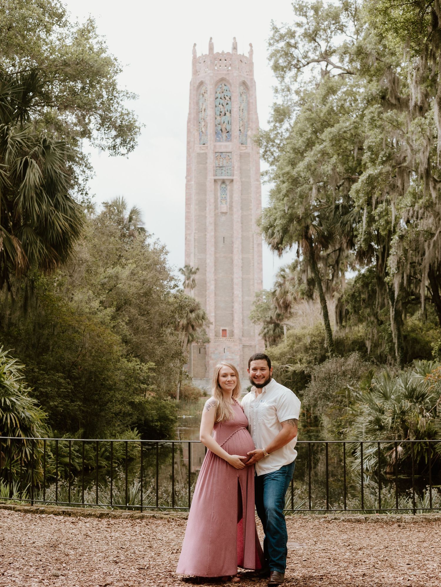 A romantic couple poses together in an outdoor garden setting with a historic church tower in the background at Bok Tower Gardens.